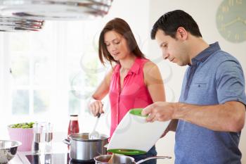 Hispanic Couple Cooking Meal At Home Together