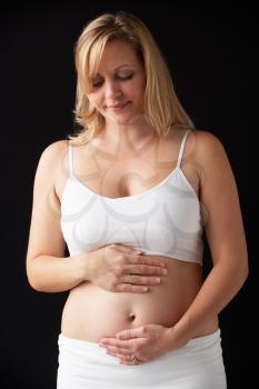 Portrait Of 4 months Pregnant Woman Wearing White On Black Background