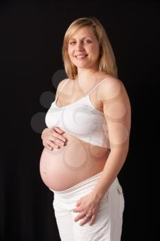 Portrait Of 6 months Pregnant Woman Wearing White On Black Background