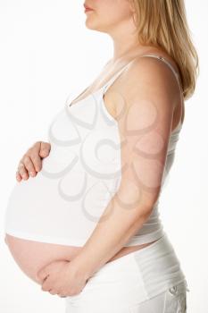 Close Up Studio Portrait Of 8 Months  Pregnant Woman Wearing White