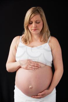 Portrait Of 9 months Pregnant Woman Wearing White On Black Background
