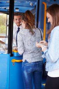 Two Young Women Boarding Bus And Buying Ticket