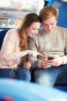 Teenage Couple Reading Text Message On Bus