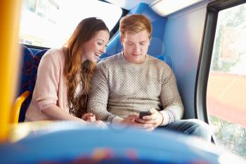 Teenage Couple Reading Text Message On Bus