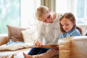 Mother And Daughter Reading Story At Home Together