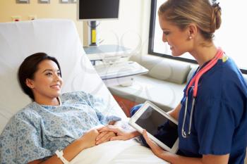 Nurse Talking To Female Patient On Ward Using Digital Tablet