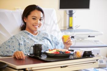 Female Patient Enjoying Meal In Hospital Bed