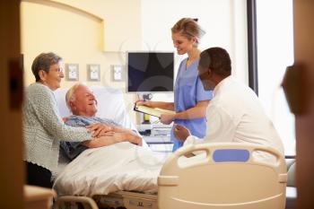 Medical Team Meeting With Senior Couple In Hospital Room