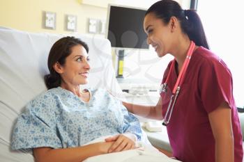 Nurse Talking To Female Patient In Hospital Room