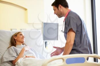 Male Nurse Talking With Female Patient In Hospital Room
