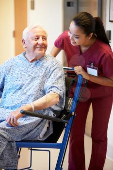 Senior Male Patient Being Pushed In Wheelchair By Nurse