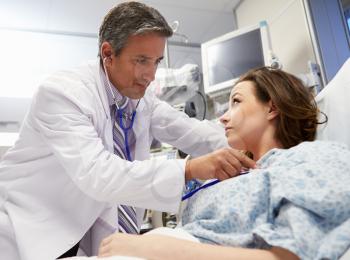 Male Doctor Examining Female Patient In Emergency Room