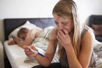 Worried Teenage Girl In Bedroom With Pregnancy Testing Kit
