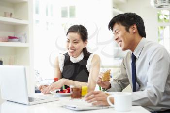 Asian Couple Looking at Laptop Over Breakfast
