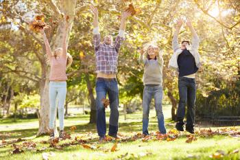 Family Throwing Autumn Leaves In The Air