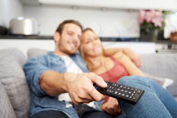 Young Couple Sitting On Sofa Watching Television