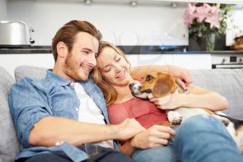 Young Couple Playing With Pet Dog At Home