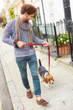 Man Taking Dog For Walk On City Street