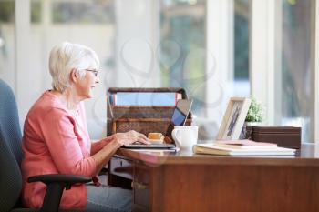 Senior Woman Using Laptop On Desk At Home
