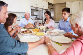 Multi-Generation Family Saying Prayer Before Eating Meal