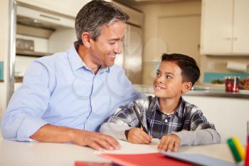 Hispanic Father Helping Son With Homework At Table