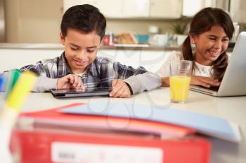 Children Using Laptop And Digital Tablet To Do Homework