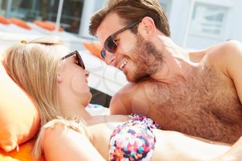 Young Couple On Holiday Relaxing By Swimming Pool