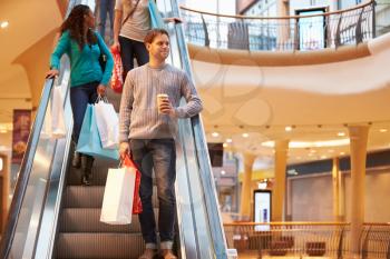 Male Shopper On Escalator In Shopping Mall