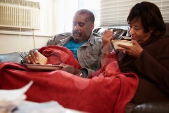 Senior Couple With Poor Diet Keeping Warm Under Blanket