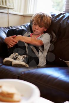 Unhappy Boy Sitting On Sofa At Home
