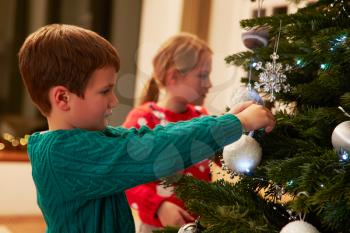 Children Decorating Christmas Tree At Home