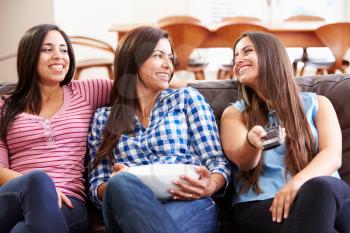 Group Of Women Sitting On Sofa Watching TV Together