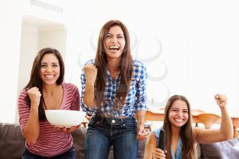 Group Of Women Sitting On Sofa Watching Sport Together