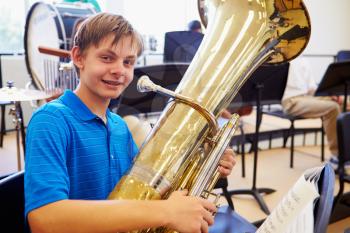Male Pupil Playing Tuba In High School Orchestra