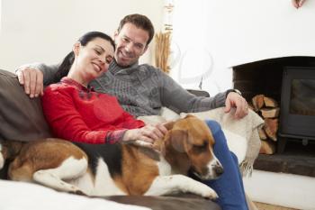 Couple Relaxing At Home With Pet Dog