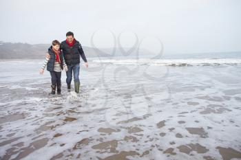 Father And Son Walking On Winter Beach