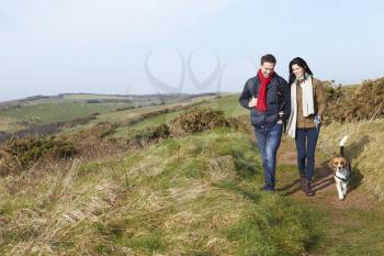 Couple With Dog Walking Along Coastal Path