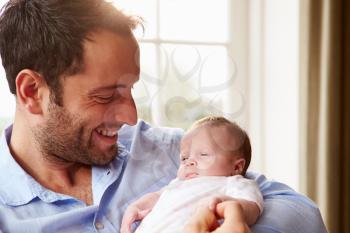 Father At Home With Newborn Baby Daughter