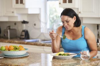 Fed Up Overweight Woman Eating Healthy Meal in Kitchen