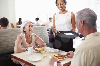 Waitress Serving Senior Couple Breakfast In Hotel Restaurant