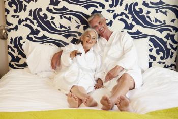 Senior Couple Relaxing In Hotel Room Watching Television