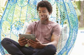 Man On Outdoor Garden Swing Seat Using Digital Tablet