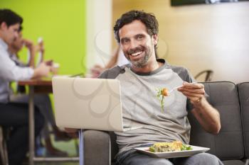 Man Sitting On Sofa And Eating Lunch In Design Studio