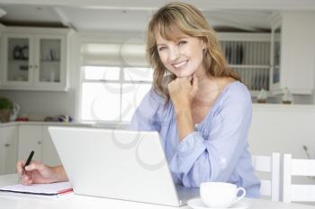 Mid age woman working at home on laptop