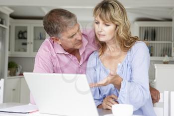 Mid age couple working at home on laptop