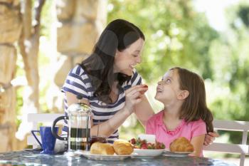 Mother and daughter eating breakfast outdoors