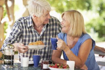 Senior couple eating breakfast outdoors