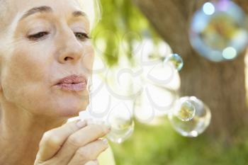 Senior woman blowing bubbles outdoors