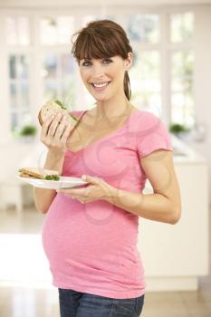 Pregnant woman eating sandwich