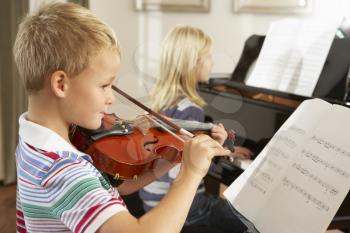 Boy and girl playing violin and piano at home